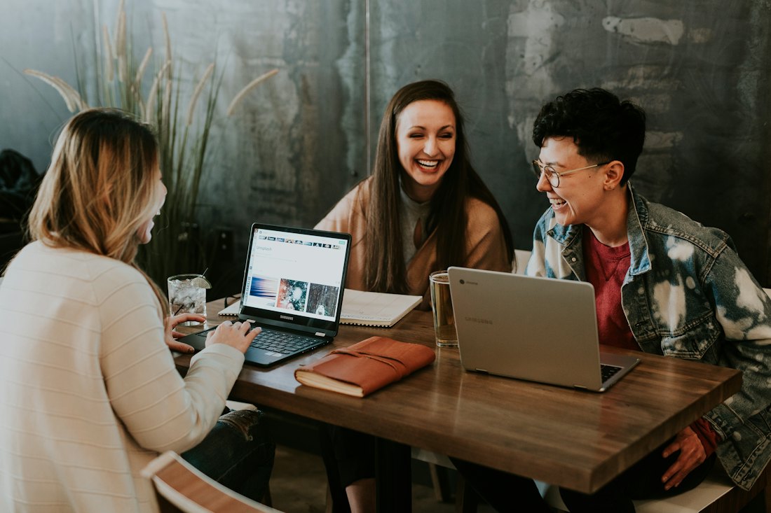 Three colleagues working together at a table with laptops